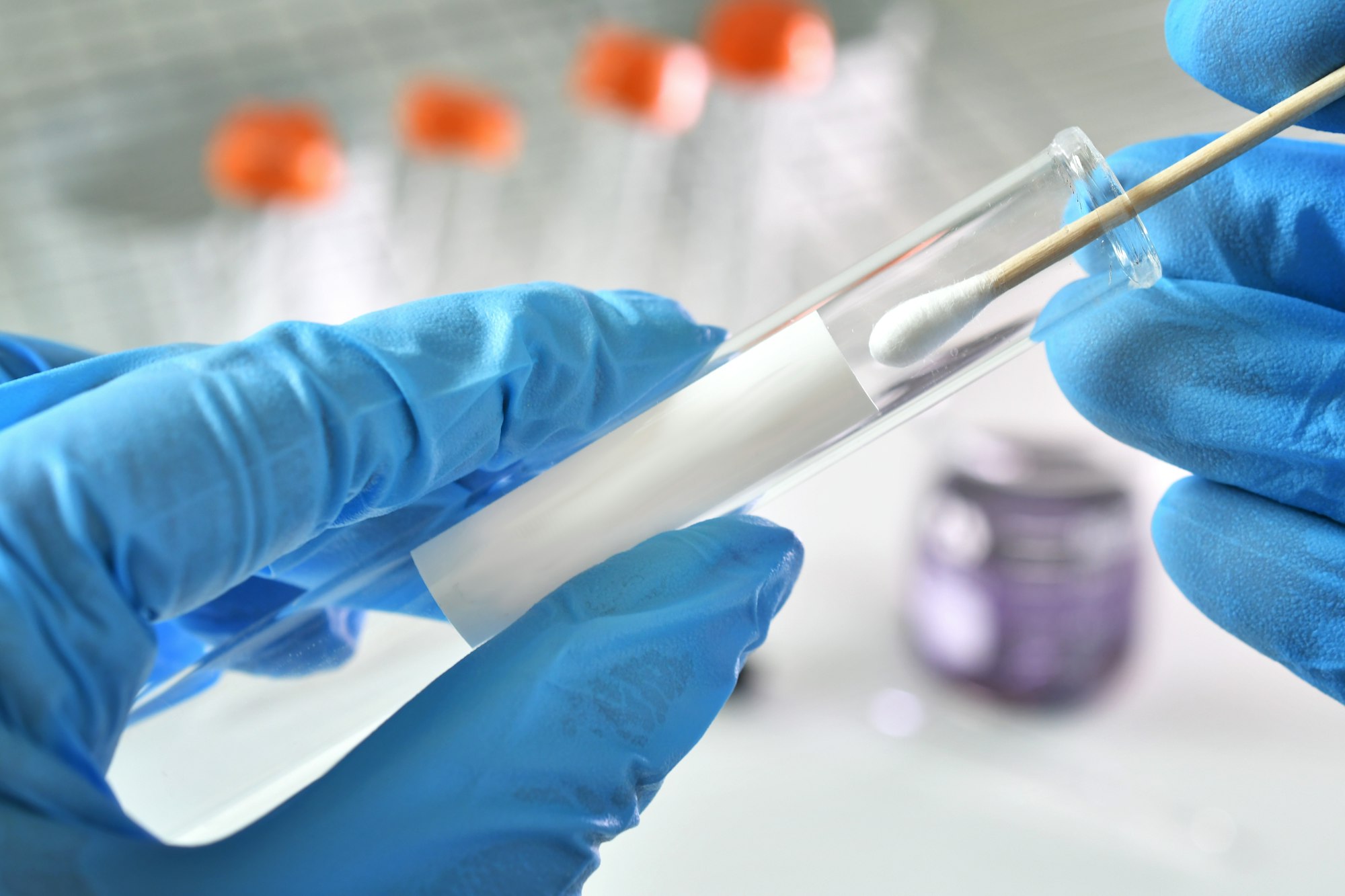 Nasal or oral testing swab being inserted test tube with blank label for mock up