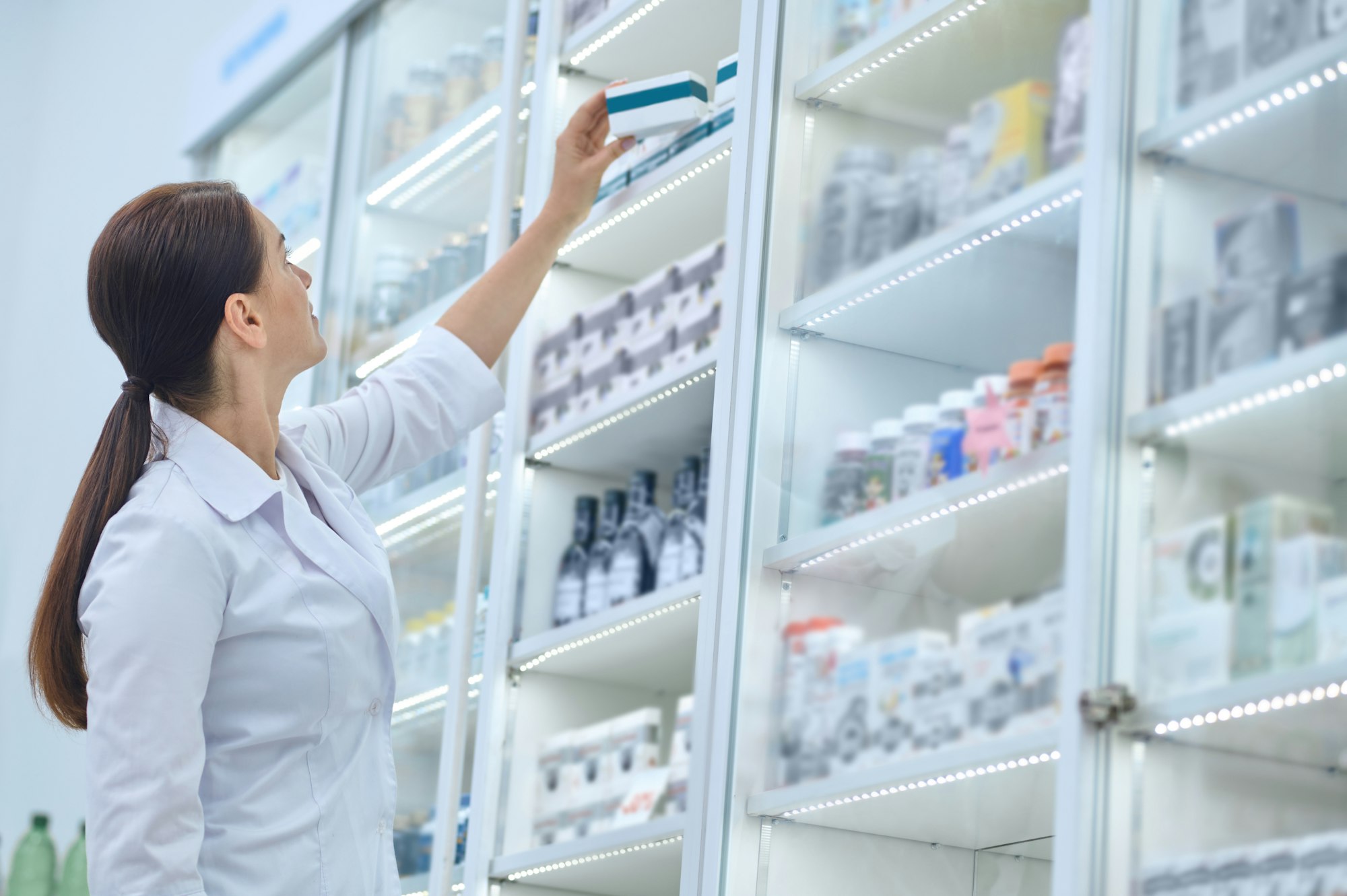 Pharmaceutist reaching for medications on pharmacy shelves