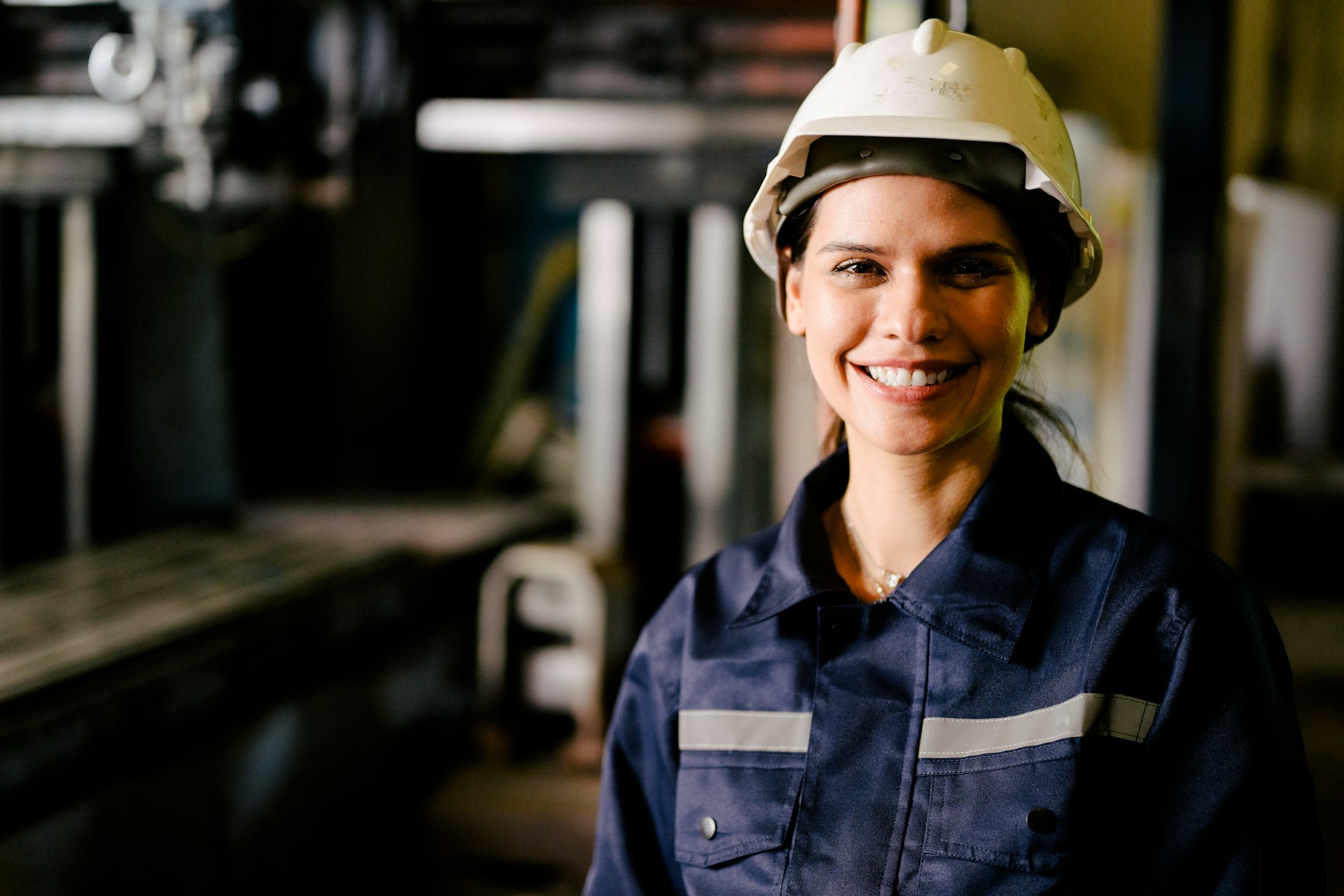 Portrait of happy female industrial worker in white hard hat smiling