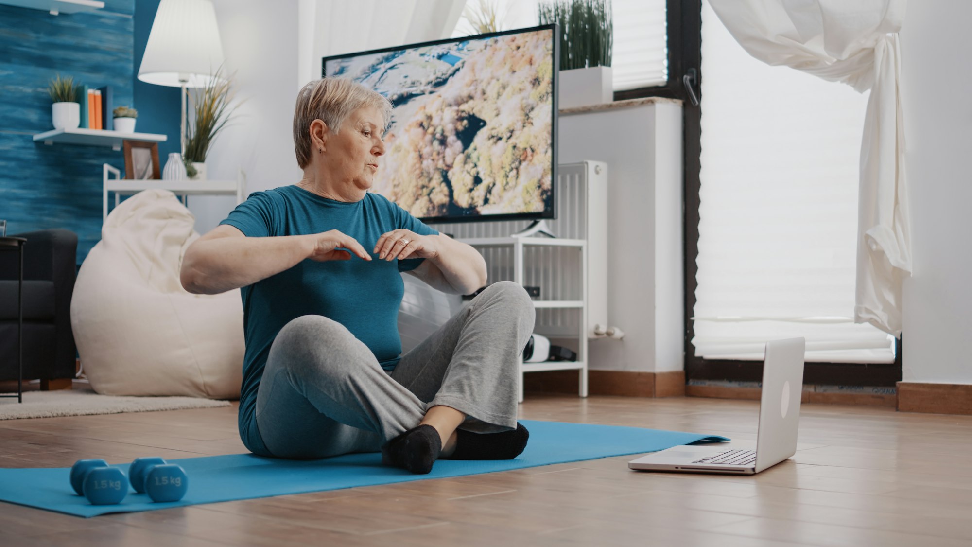 Senior woman following training video program on laptop