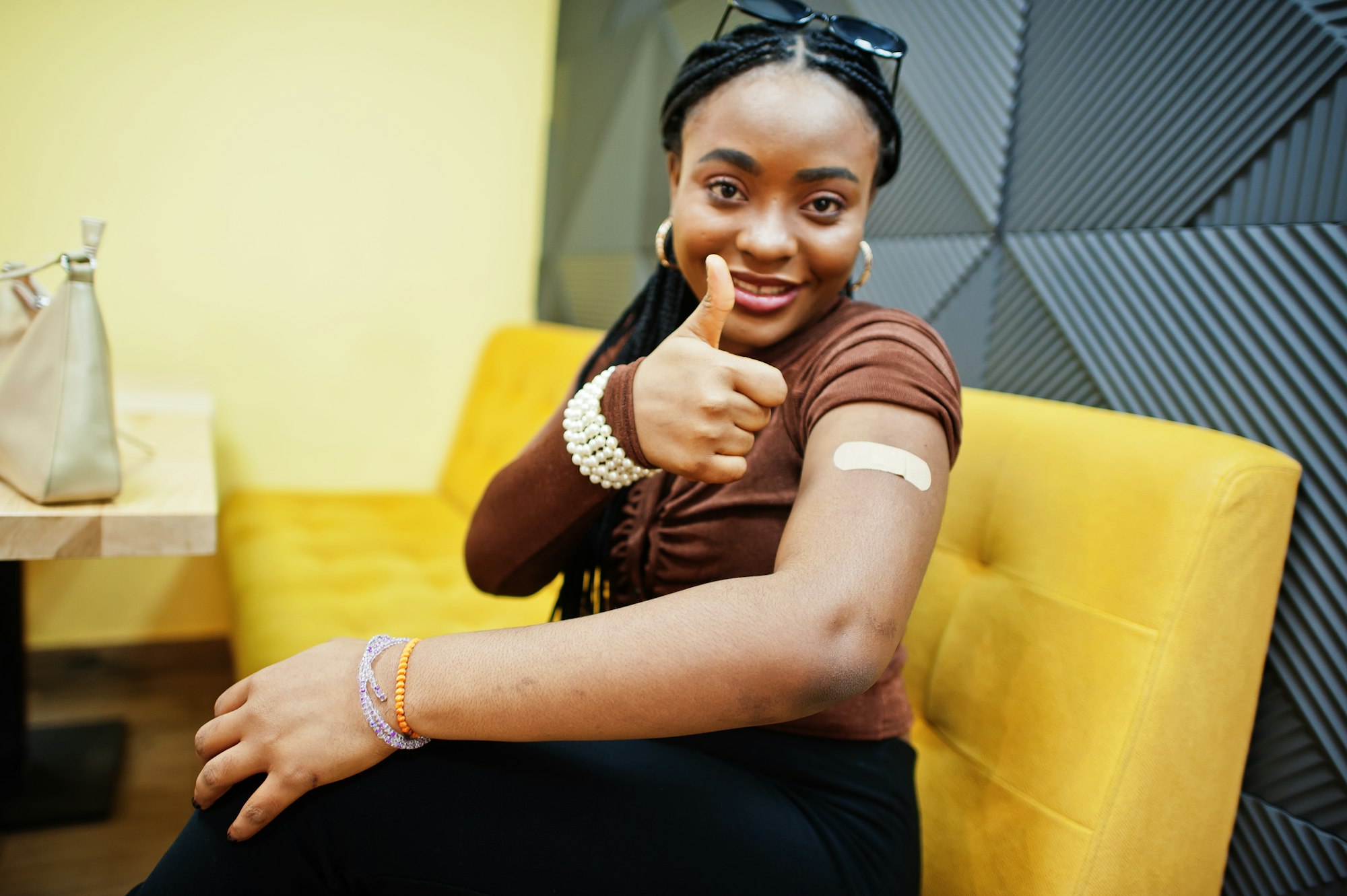 Stay safe! Black woman showing vaccinated arm after vaccine injection.