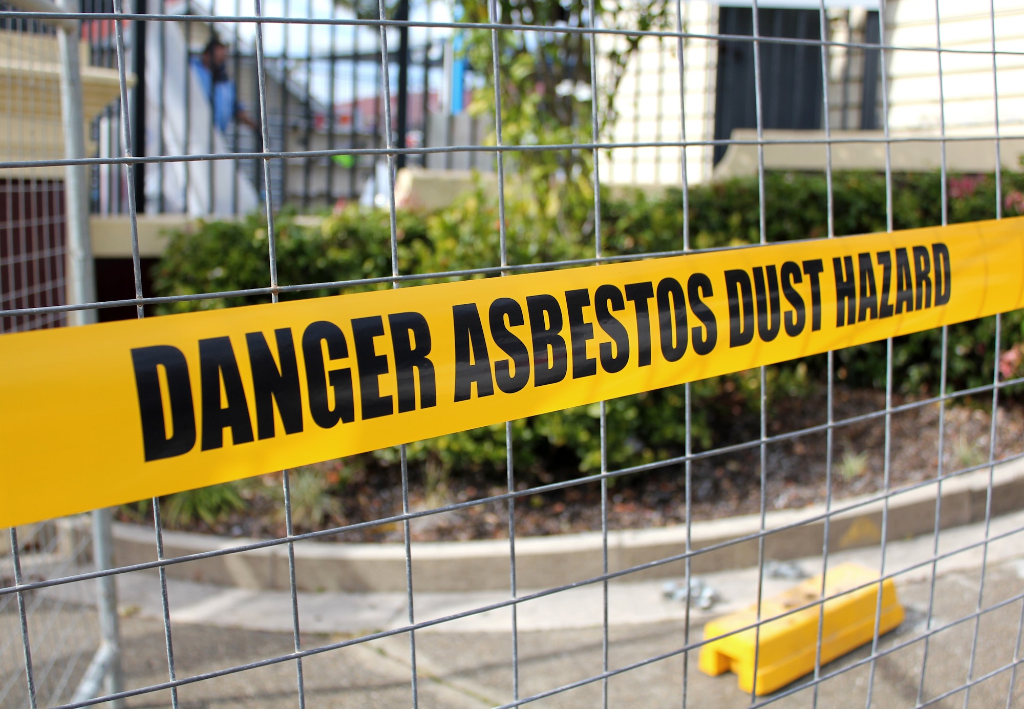 Yellow caution tape warning the public on a construction site - danger asbestos dust hazard